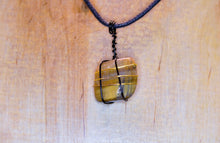 Load image into Gallery viewer, Polished Tiger&#39;s Eye Stone With Black and Gold Wire Wrapping With a Black Cord
